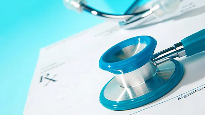Healthcare professional reviewing medical documents with stethoscope and clipboard